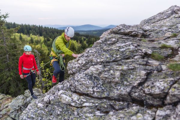 Červená a zelená bunda Rab Borealis při skalním lezení