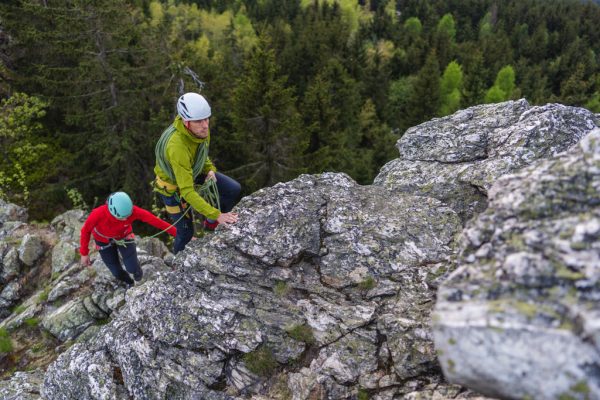 Červená a zelená bunda Rab Borealis při skalním lezení