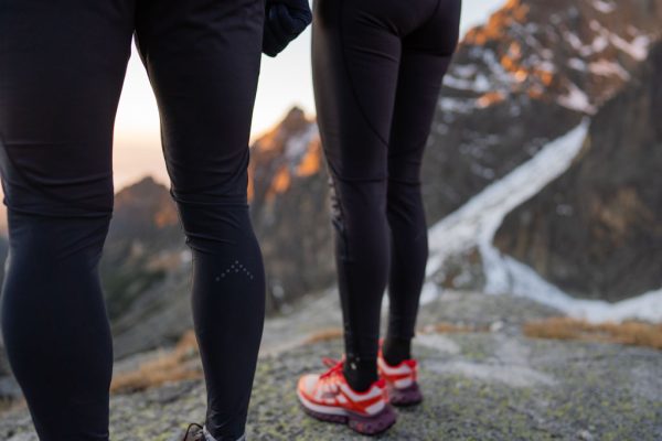 Dámské a pánské kalhoty Rab Talus Tights na horském hřebeni při západu slunce