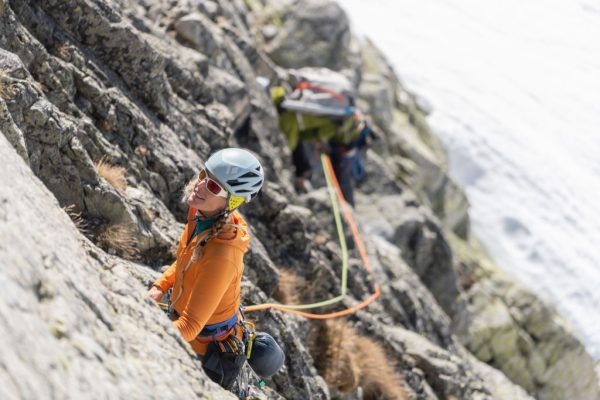 Horolezkyně v oranžové mikině Rab Ascendor Hoody ve skalní stěně.