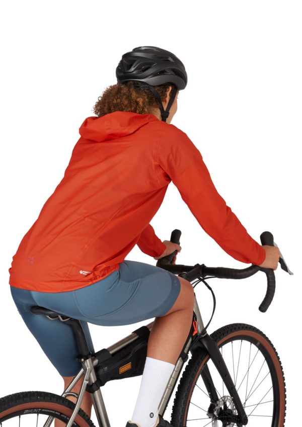 Dámská cyklistická nepromokavá bunda Rab Cinder Phantom Red Grapefruit v cyklistickém posedu na kole zepředu z boku